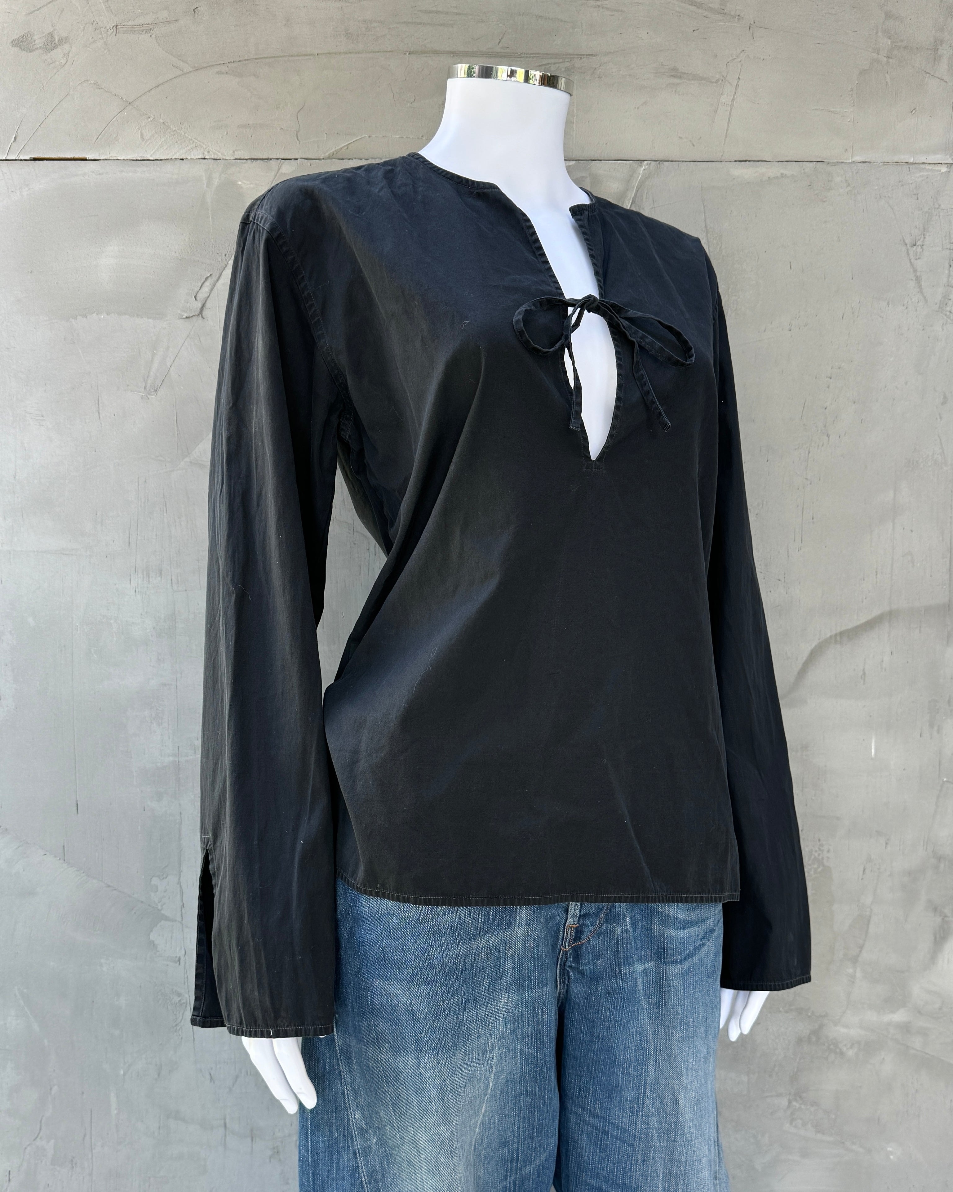 Black blouse with a bow detail on a mannequin against a gray background