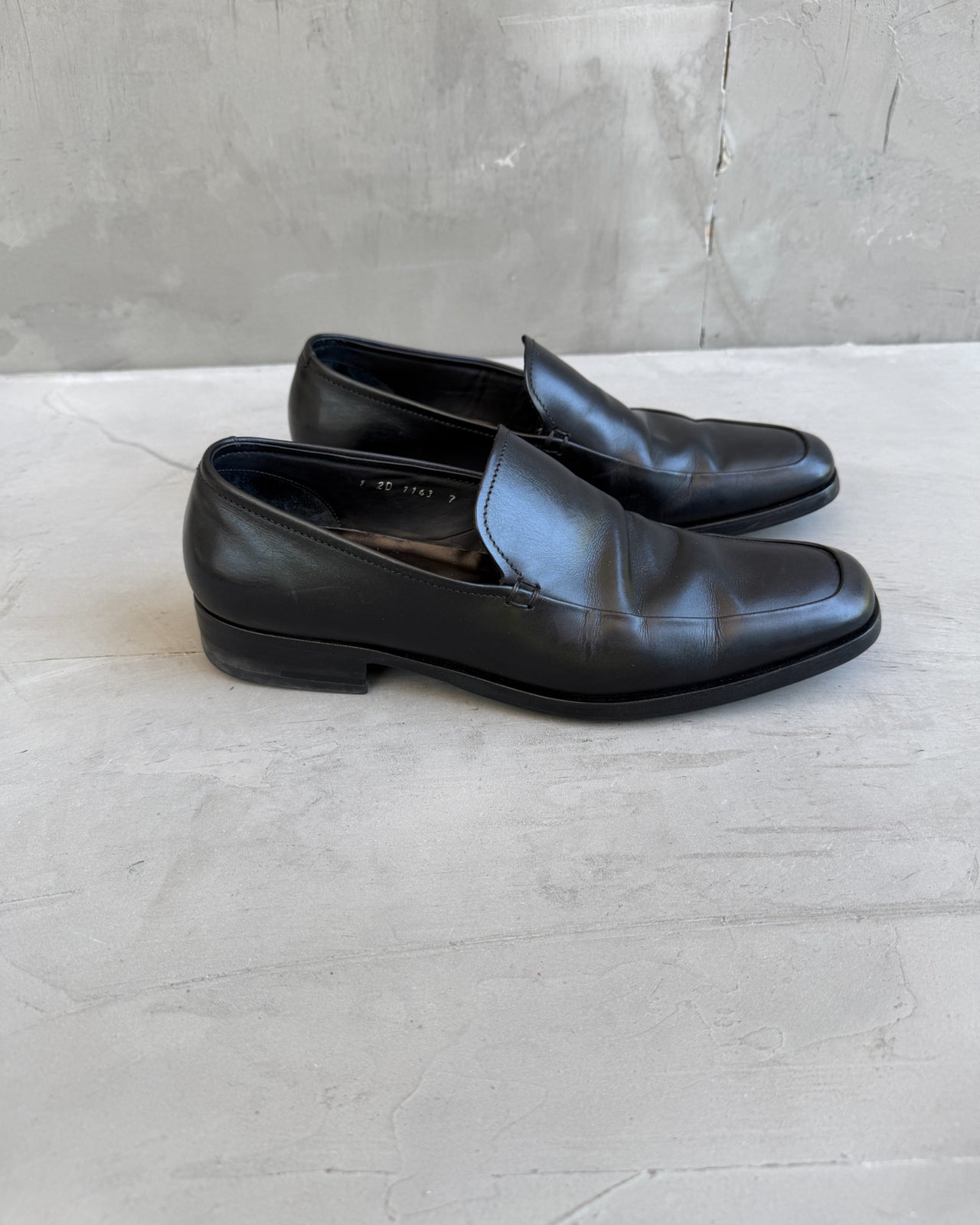 Prada Black Leather Loafers – UK 7-on a concrete background