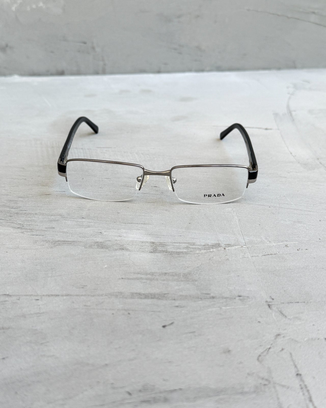 Prada Clear Lens Half Rim Glasses-on a concrete background