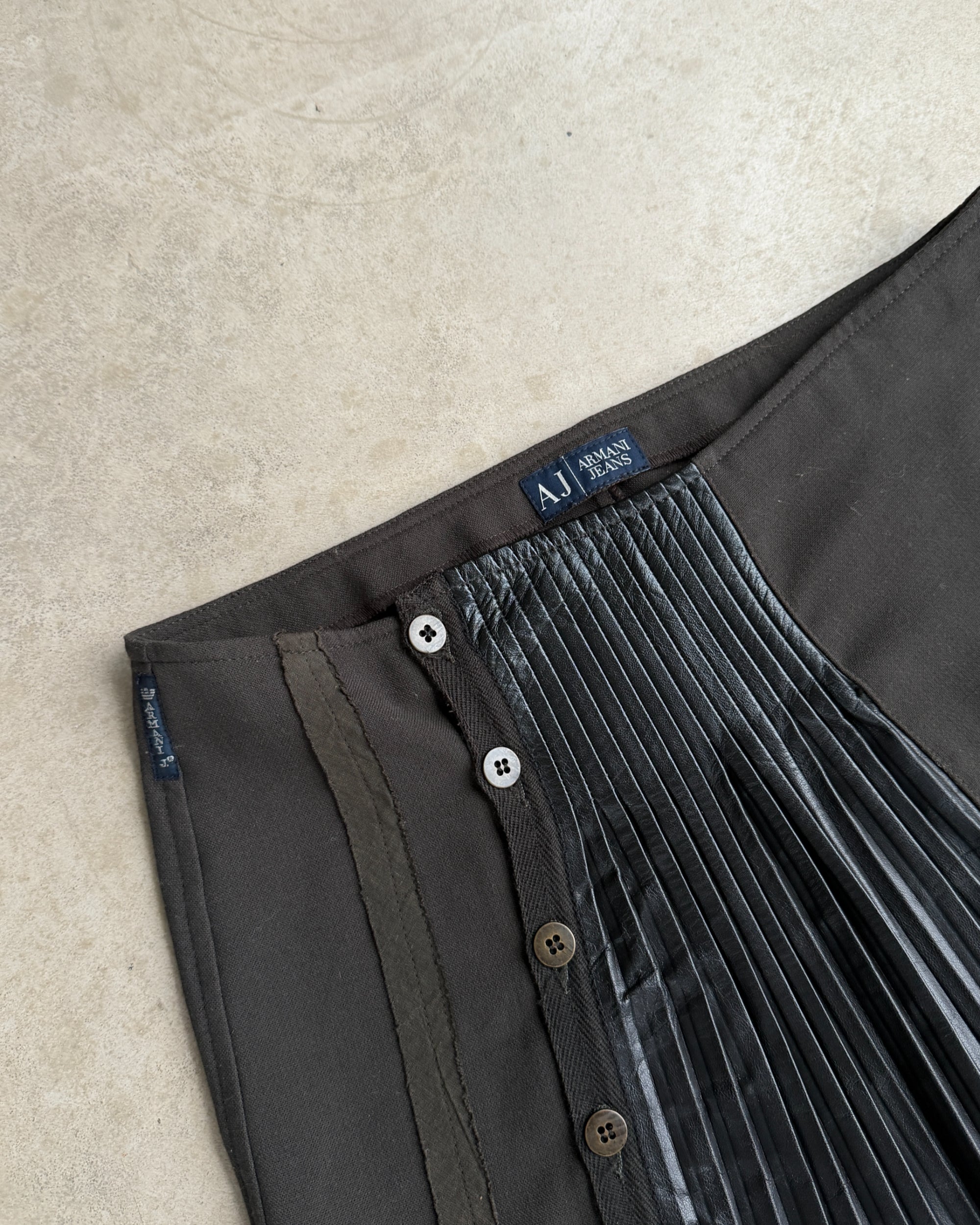 Armani Jeans Pleated Mini Skirt with Leather Panel – S-on a concrete background