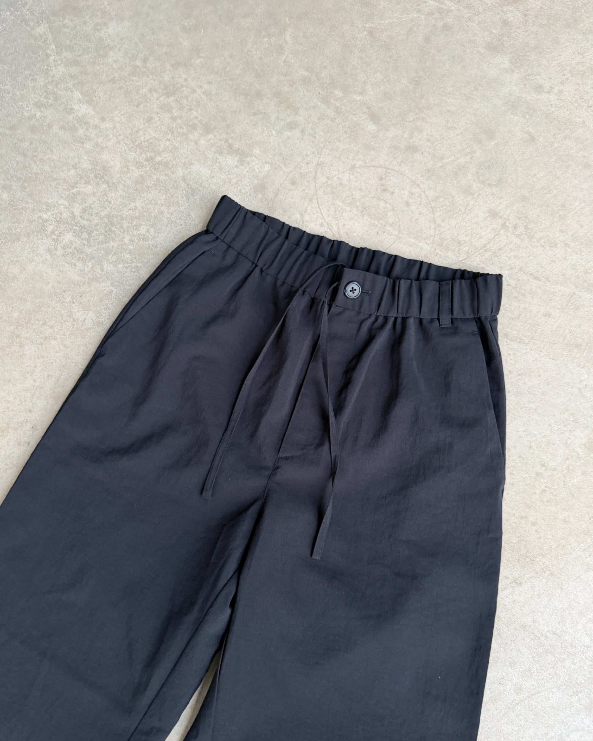 Snow Peak Black Trousers – S-on a concrete background