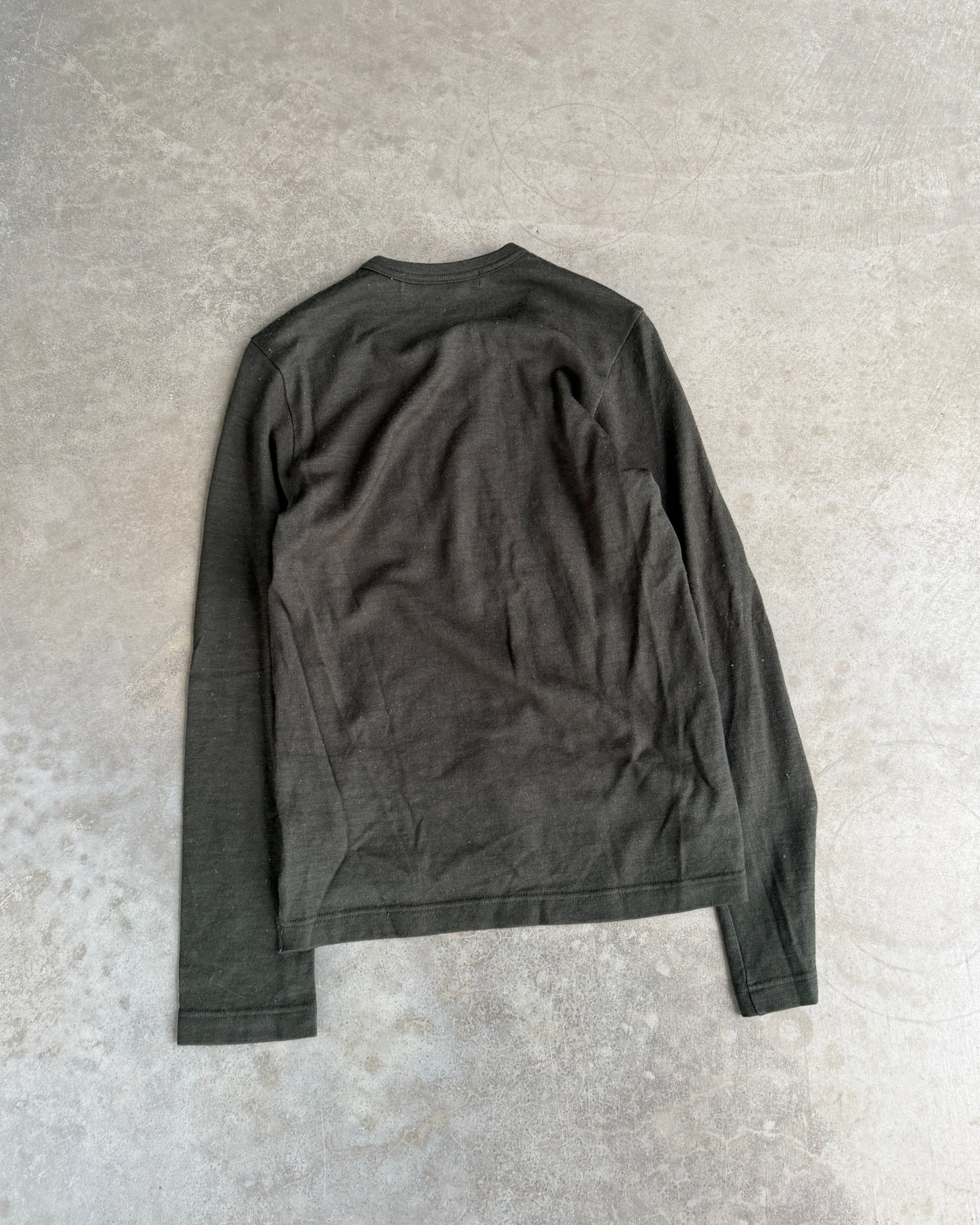 Comme des Garçons Green Asymmetric Top – XS-on a concrete background