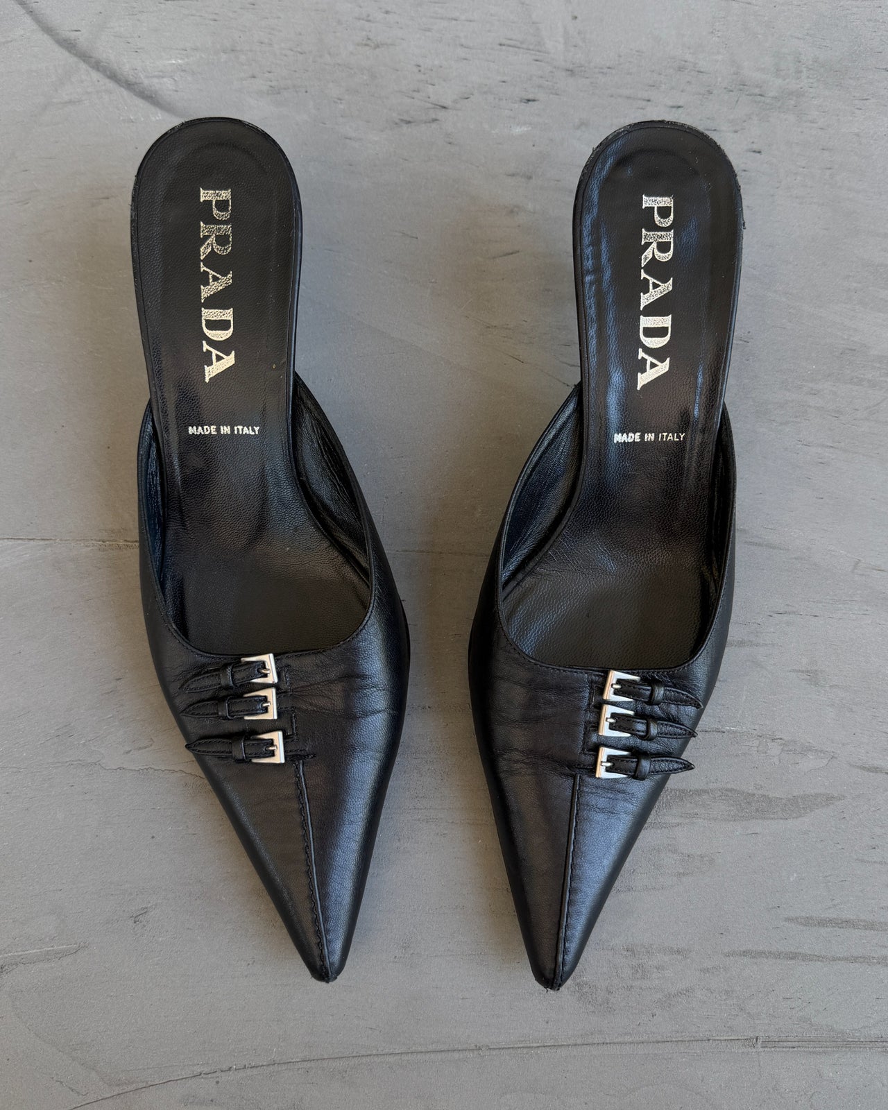 Prada Black Leather Triple Buckle Kitten Heel Mule – EU 37-on a concrete background
