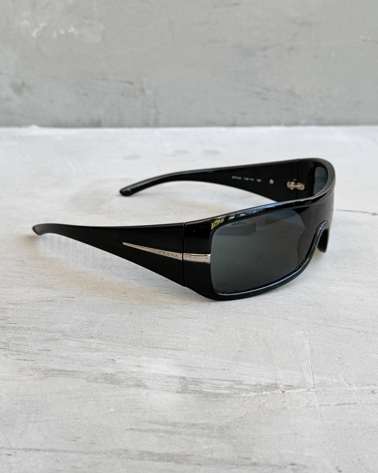 Prada Black Wraparound Sunglasses-on a concrete background
