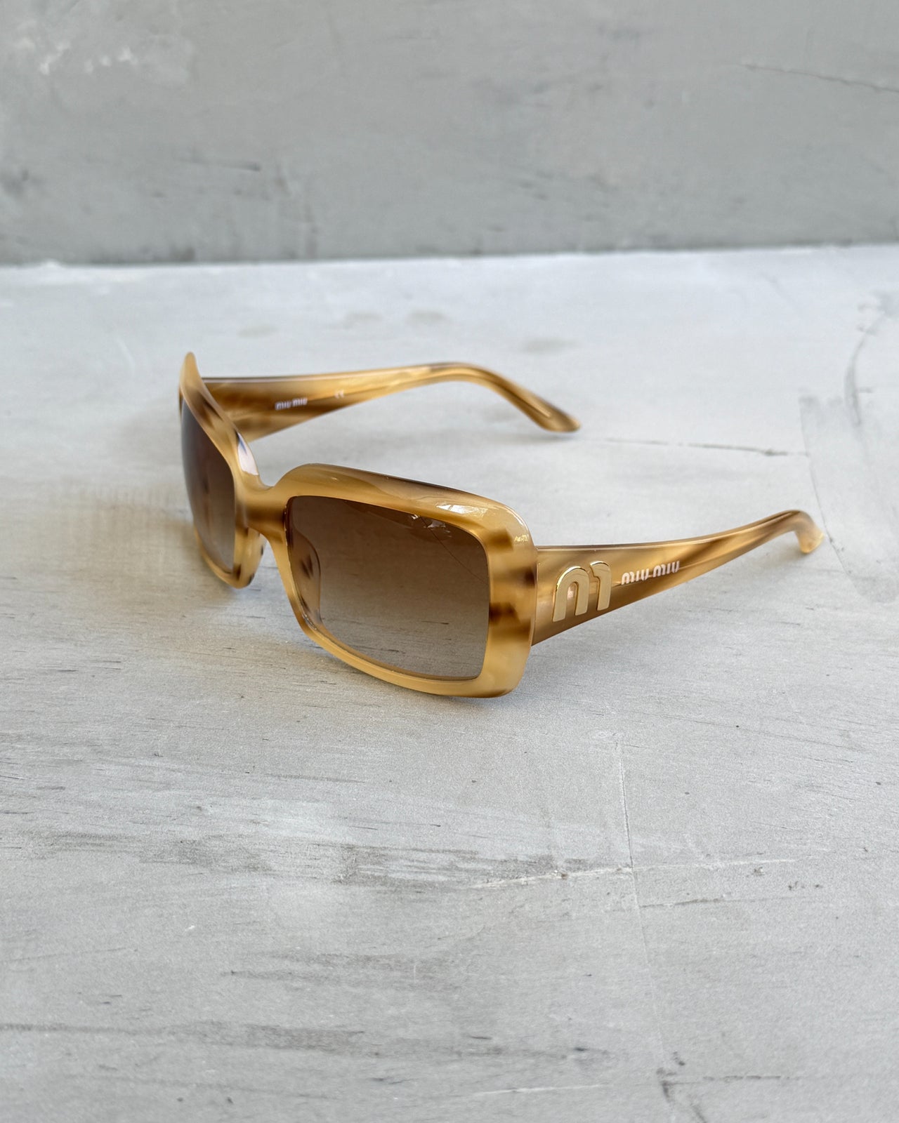 Miu Miu Beige and Brown Tortoiseshell Sunglasses-on a concrete background