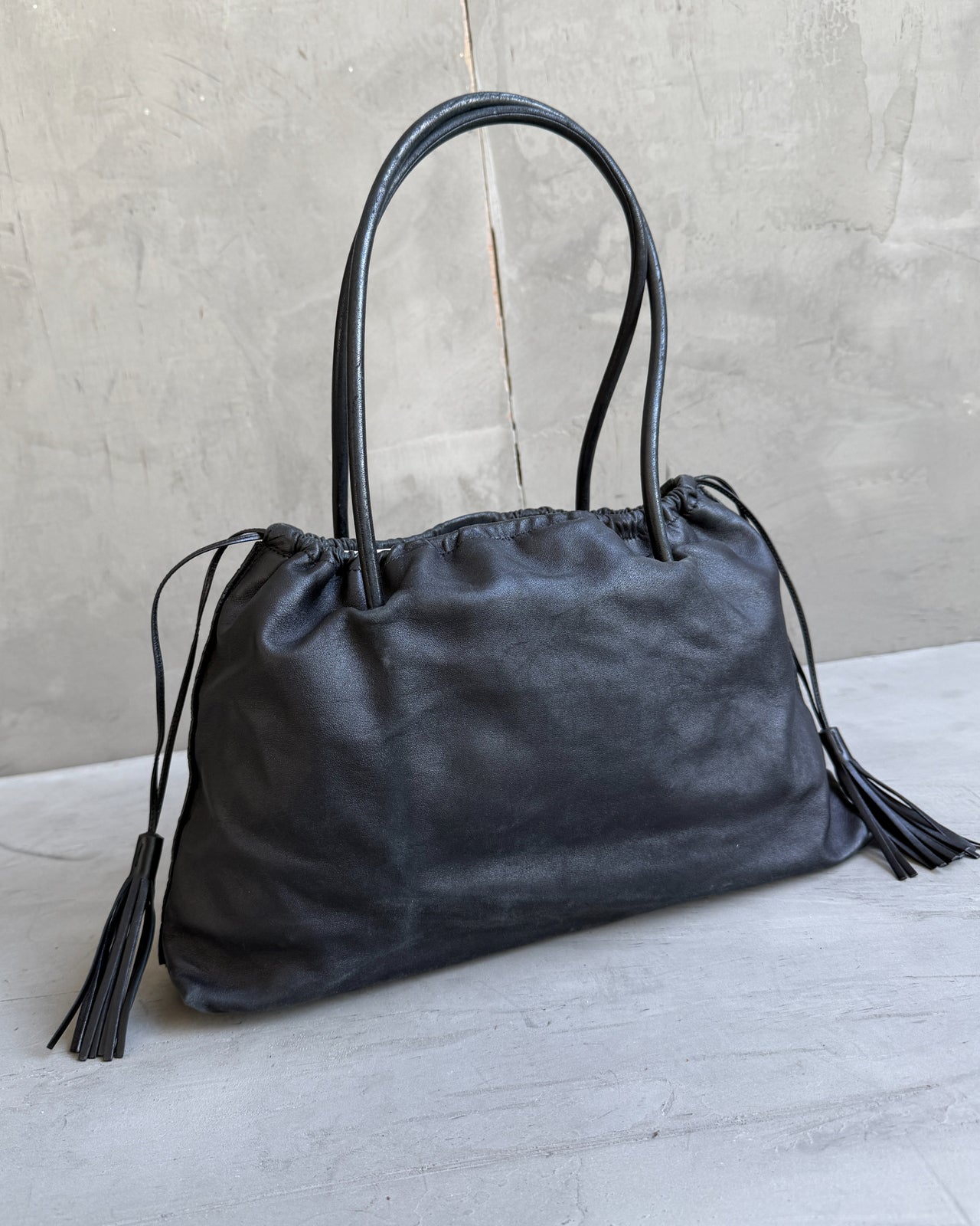 Gucci Black Leather Bag-on a concrete background