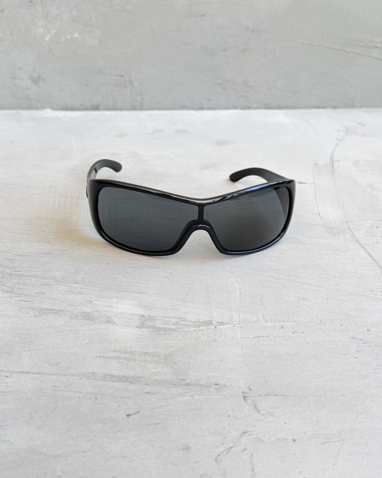 Miu Miu Black Wraparound Sunglasses-on a concrete background