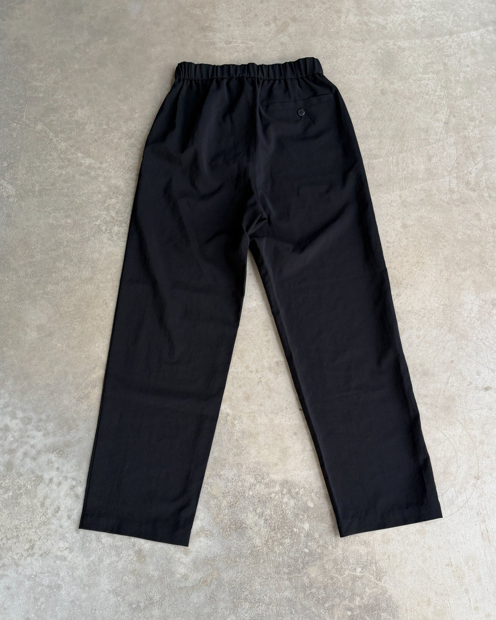 Snow Peak Black Trousers – S-on a concrete background