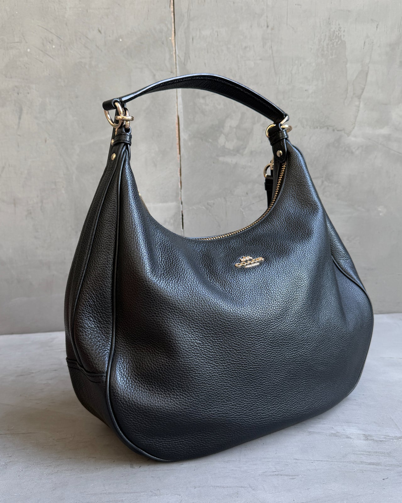 Coach Black Leather Shoulder Bag with Crossbody Strap-on a concrete background