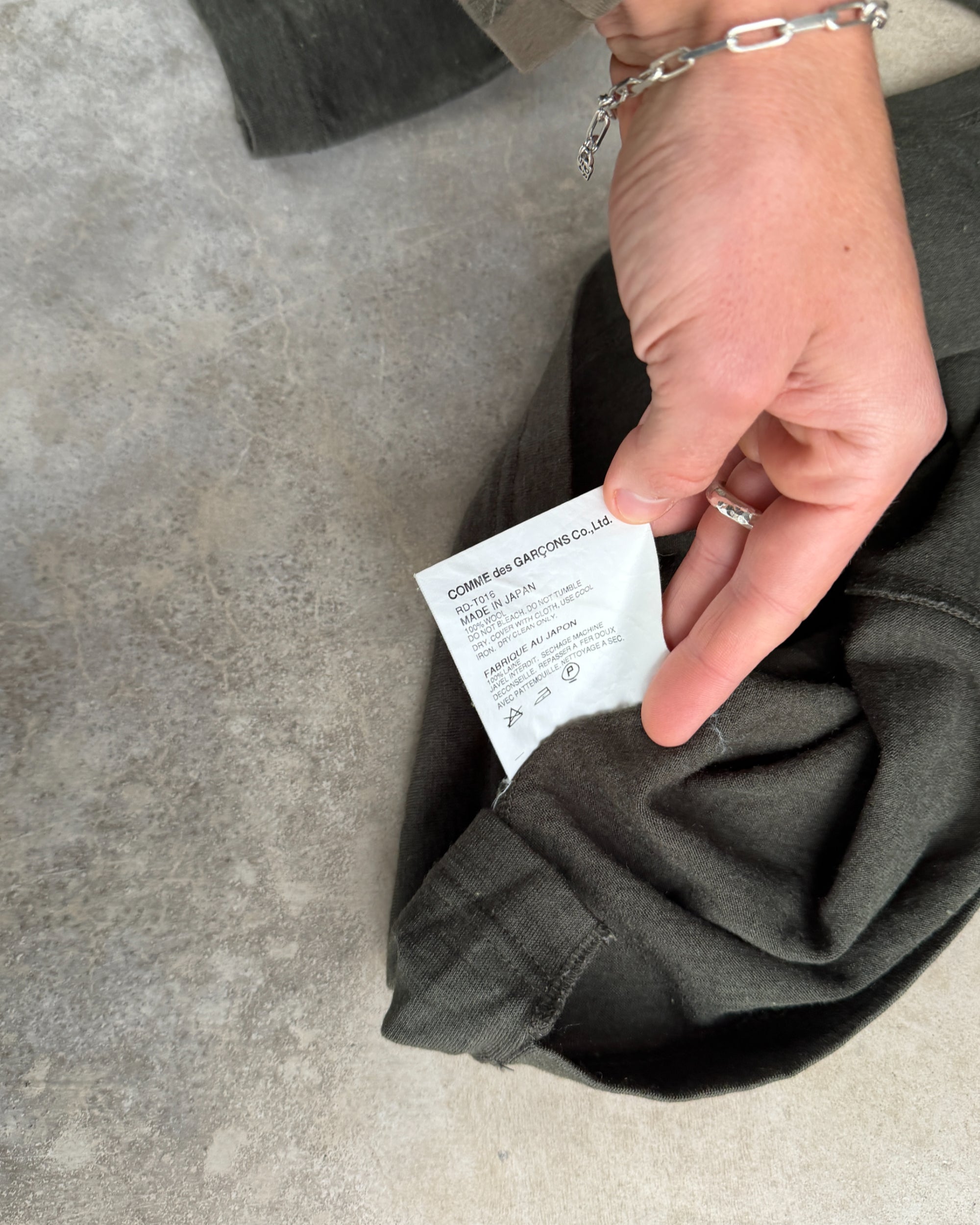 Comme des Garçons Green Asymmetric Top – XS-on a concrete background
