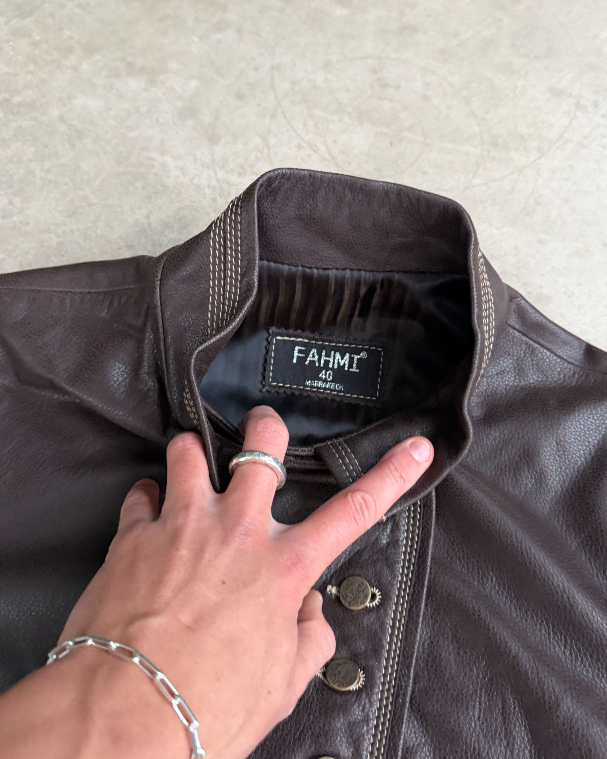 Fahmi Asymmetric Button-Up Leather Jacket – M-on a concrete background