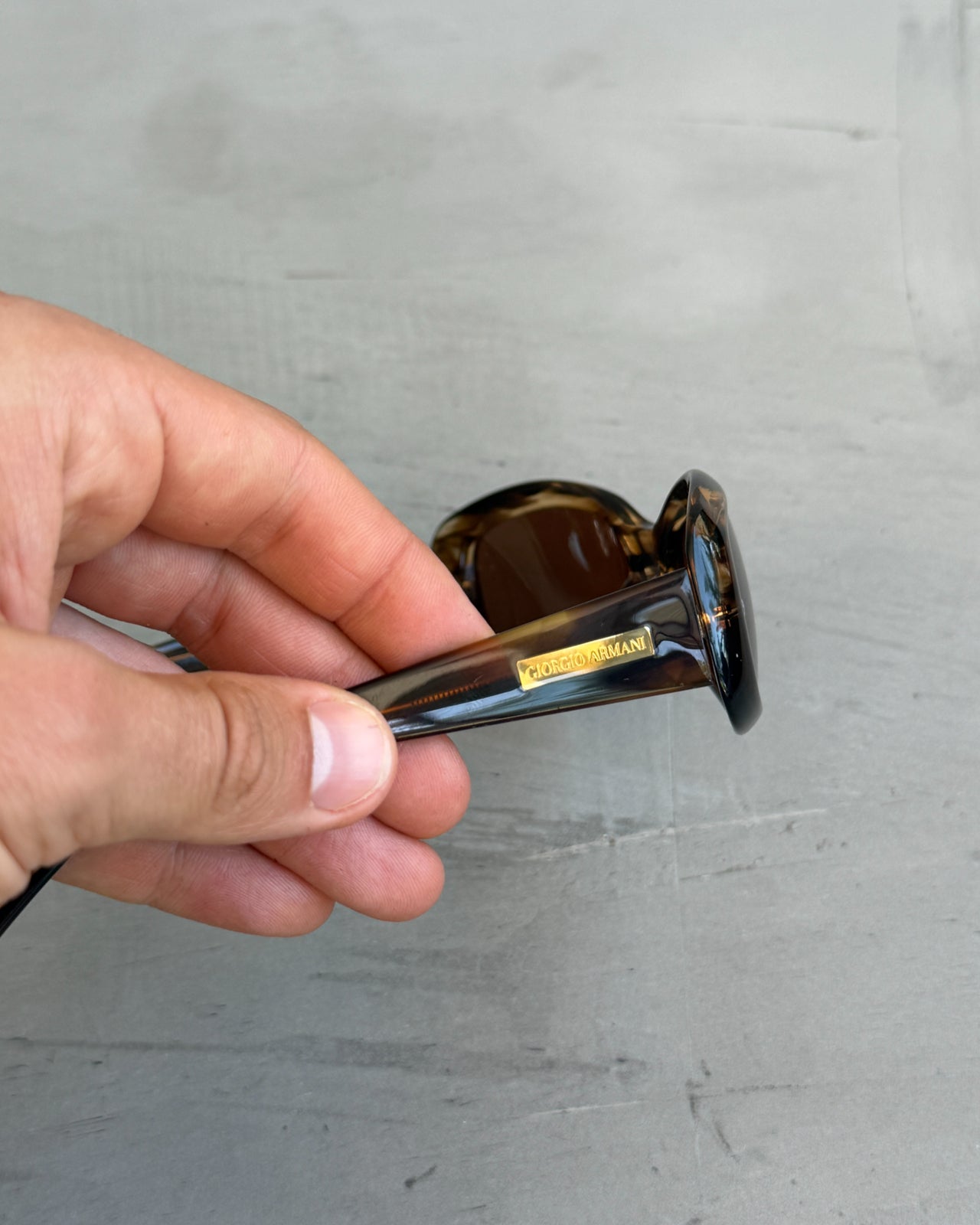 Giorgio Armani Oval Tortoiseshell Sunglasses-on a concrete background