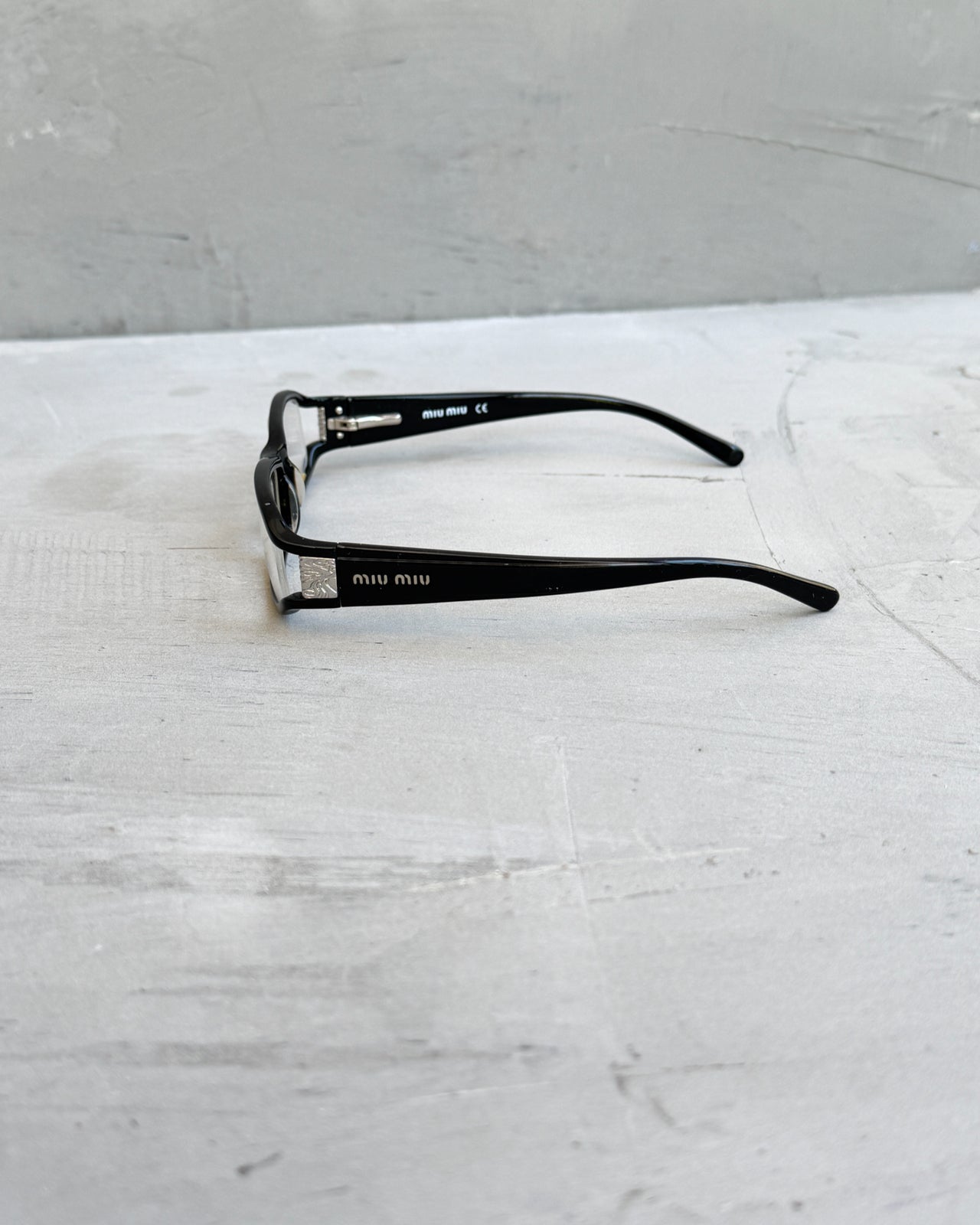 Miu Miu Black Clear Lens Glasses-on a concrete background