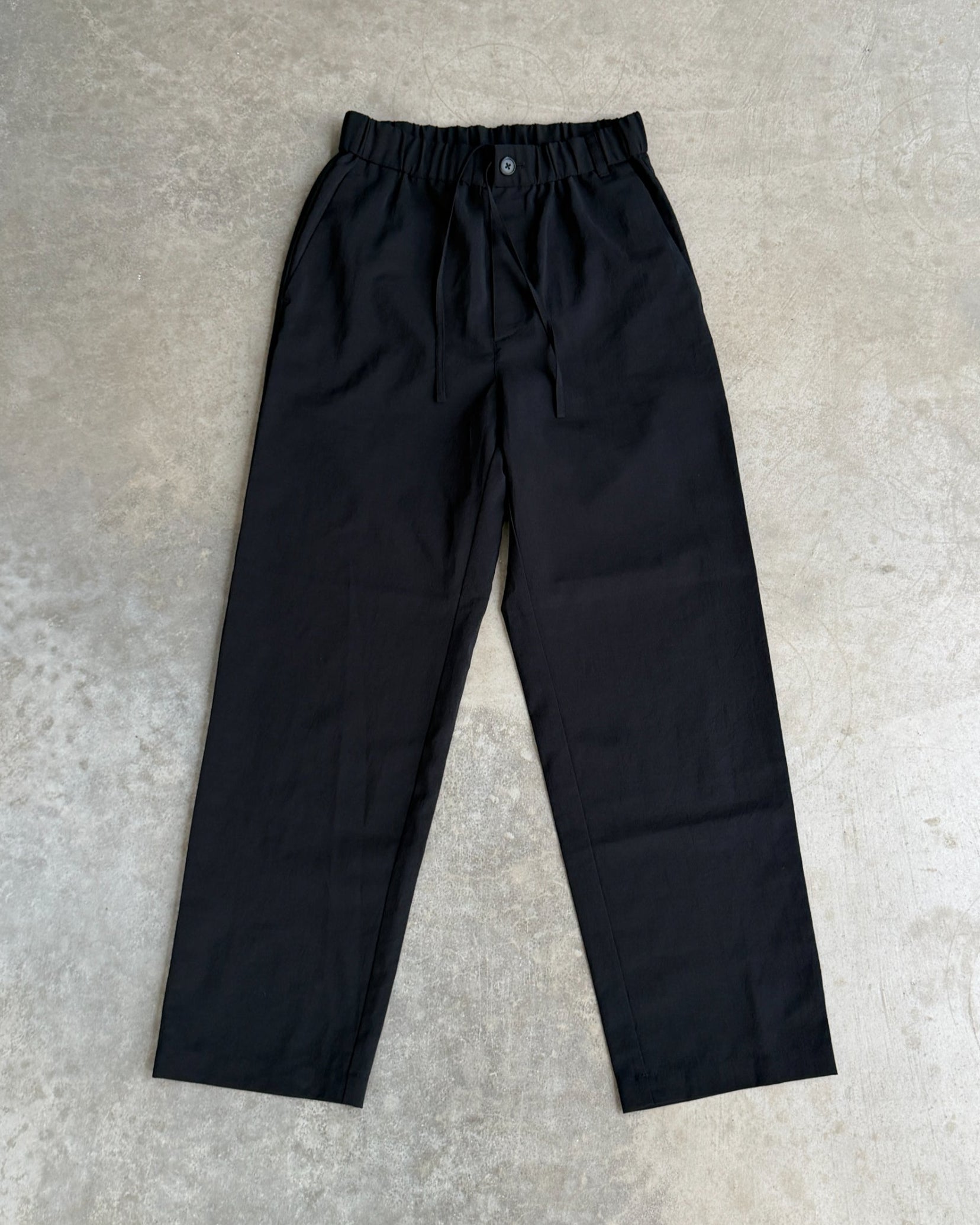 Snow Peak Black Trousers – S-on a concrete background