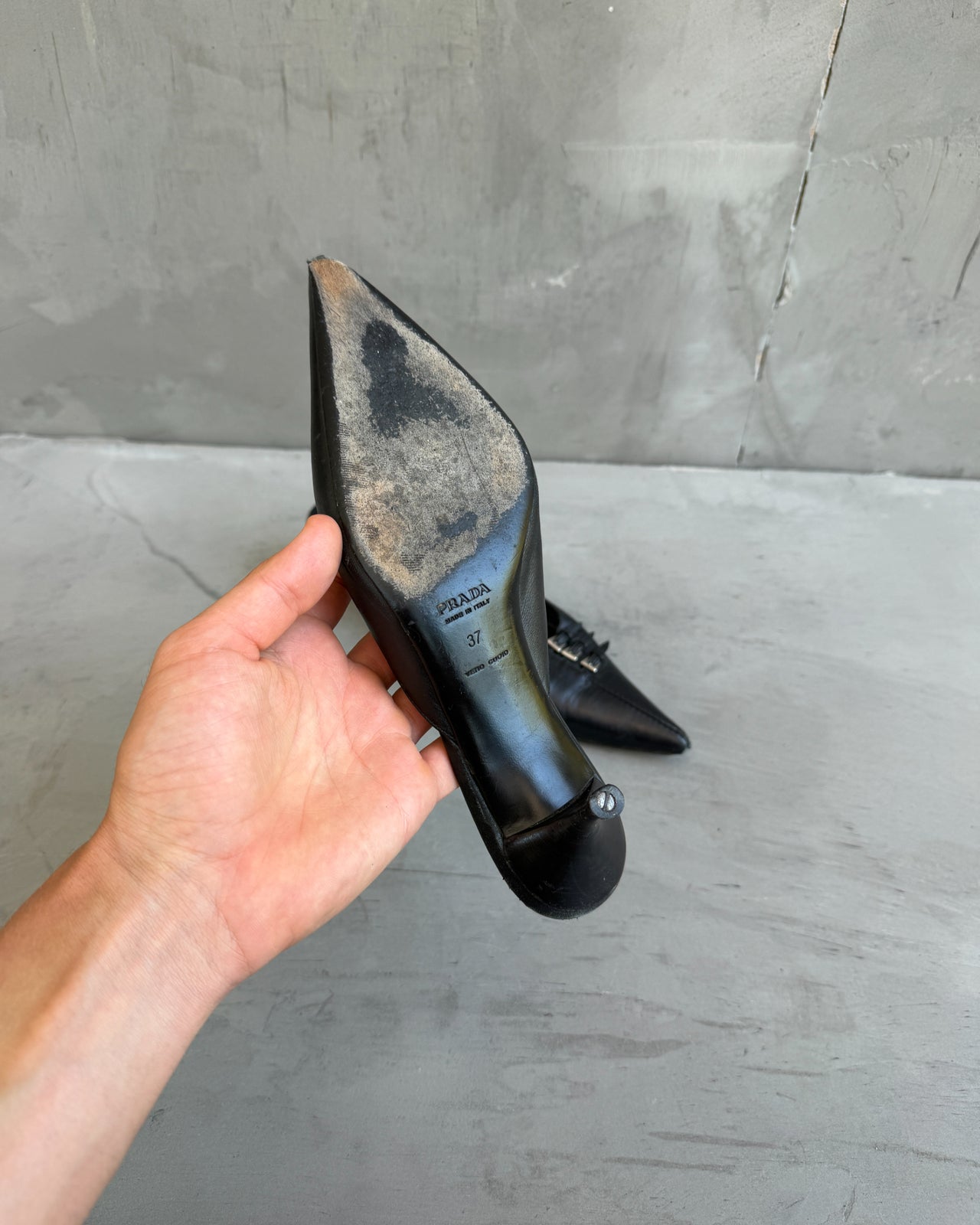 Prada Black Leather Triple Buckle Kitten Heel Mule – EU 37-on a concrete background