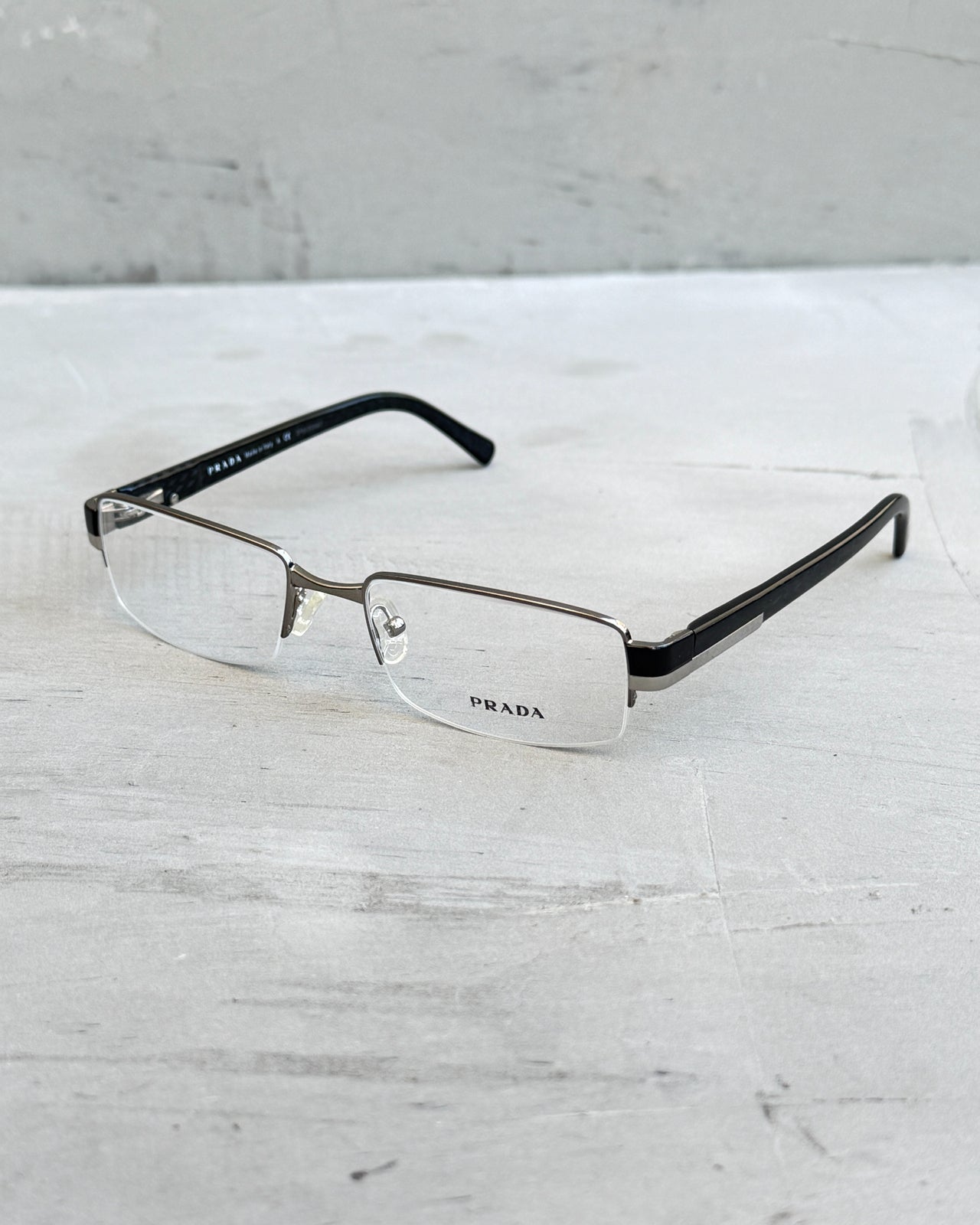 Prada Clear Lens Half Rim Glasses-on a concrete background