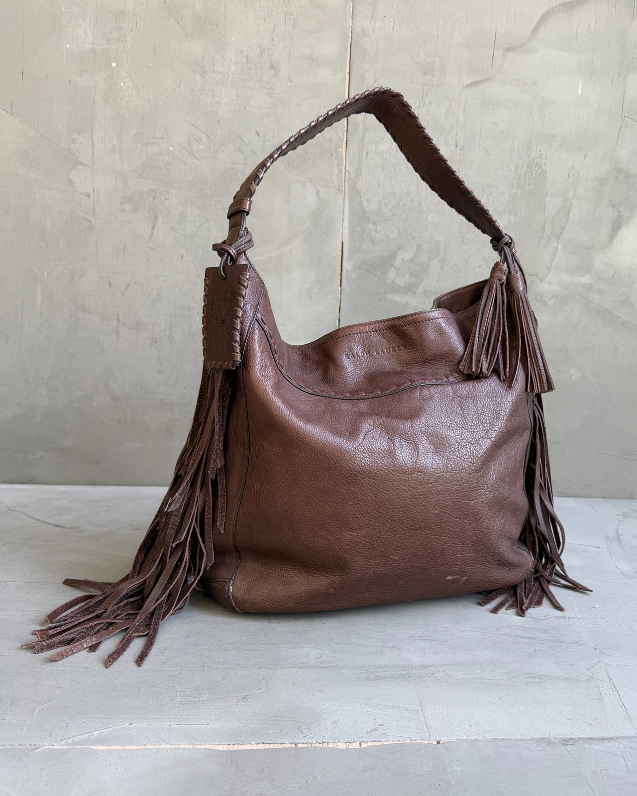 Ralph Lauren Brown Leather Fringe Shoulder Bag-on a concrete background