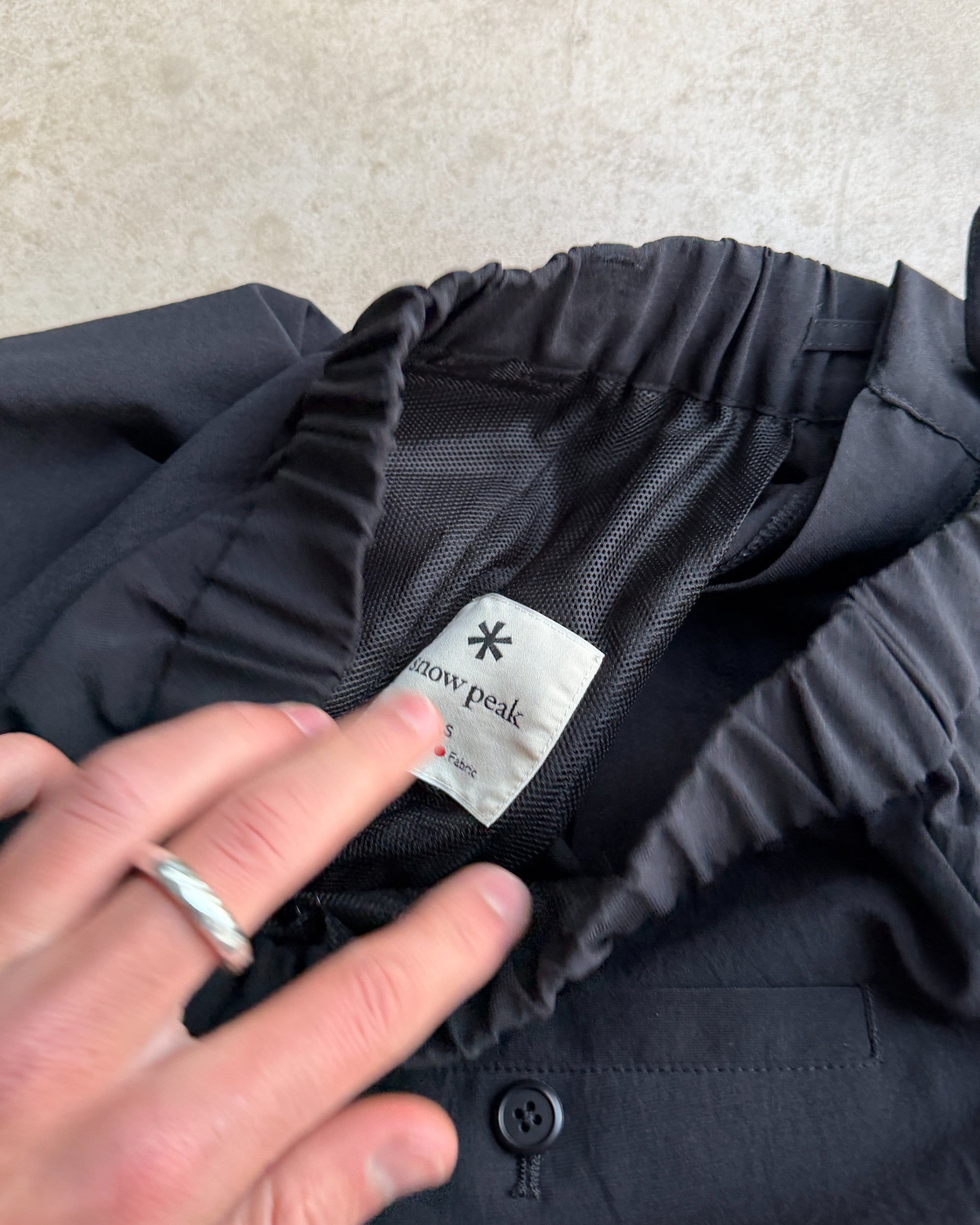Snow Peak Black Trousers – S-on a concrete background