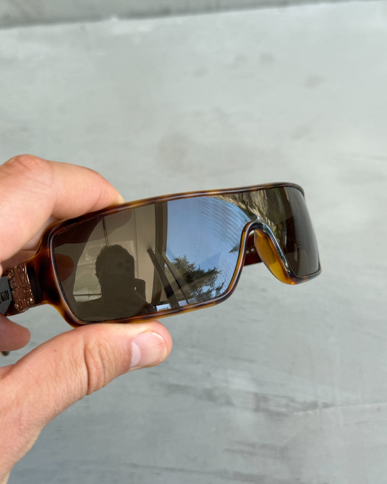 Miu Miu Brown Tortoiseshell Wraparound Sunglasses-on a concrete background