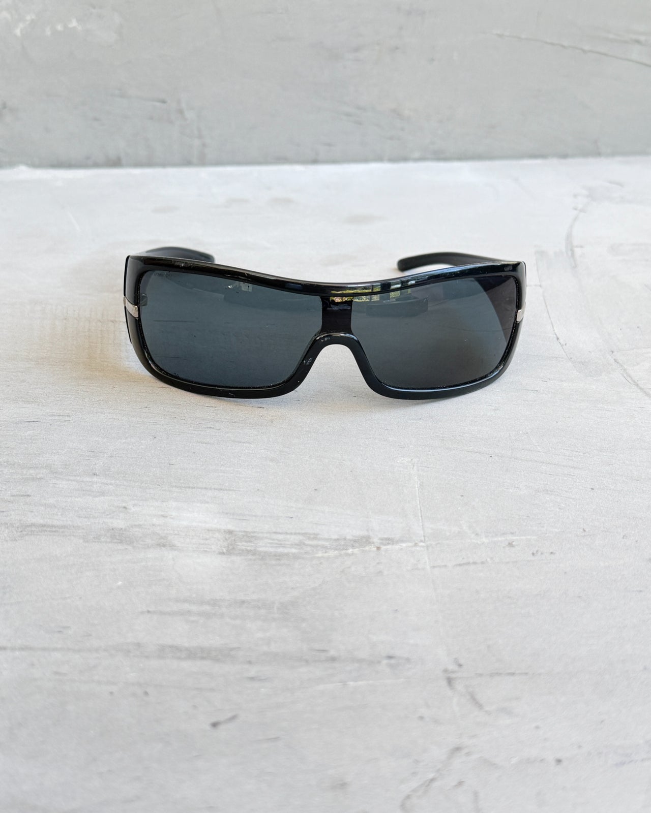 Prada Black Wraparound Sunglasses-on a concrete background