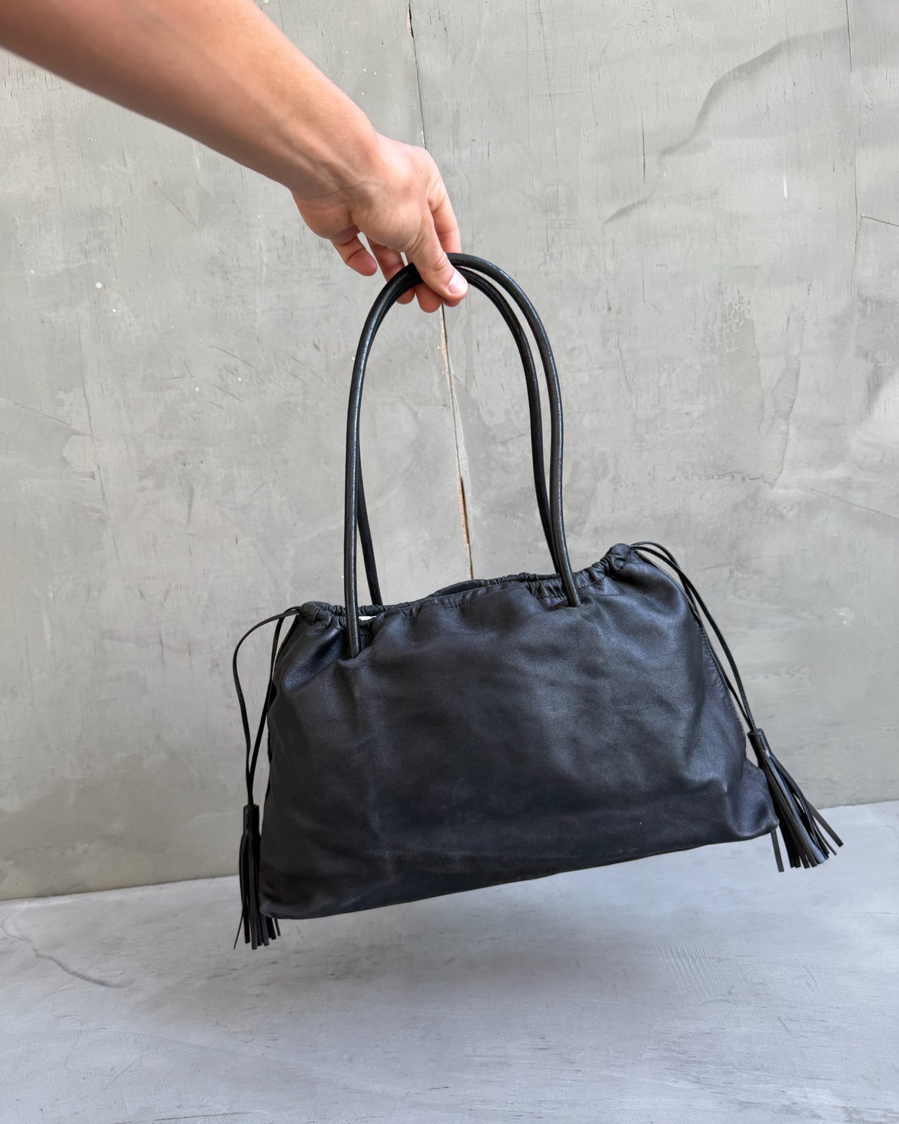 Gucci Black Leather Bag-on a concrete background